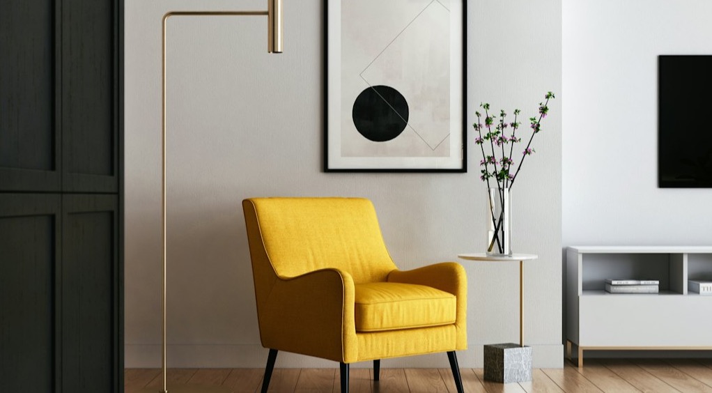Calm, comfortable room corner with a rounded armchair, smooth wood side table, and soft neutral tones